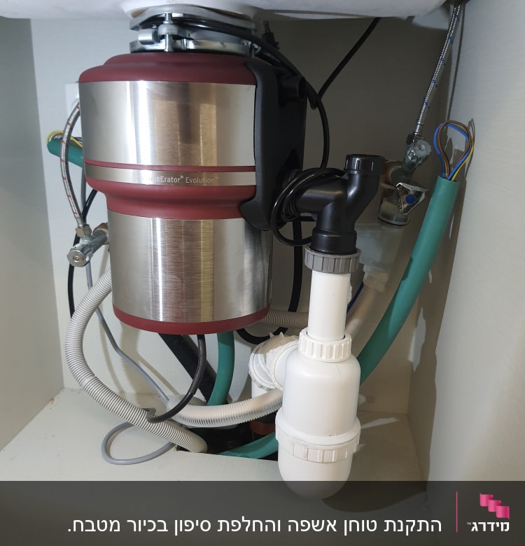 מכשיר טוחן אשפה מתחת לכיור עם צינורות מחוברים